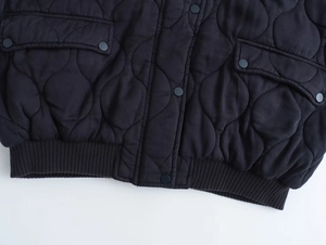 Vue détaillée d'un blouson aviateur matelassé avec boutons-pression et ourlet côtelé
