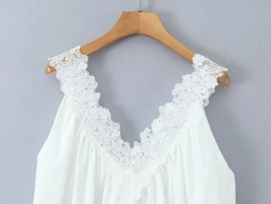 Dettaglio del bordo in pizzo e dello scollo a V su un abito bianco senza maniche