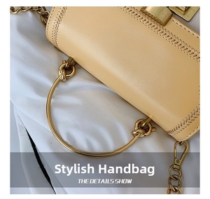 Detail of round gold metal handle and wheat-pattern stitching on beige leather bag