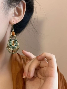 Gros plan de boucles d'oreilles vintage en bronze avec pierres oranges et perles sur mannequin
