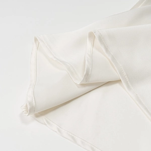 Close-up of white satin dress hem showcasing smooth fabric texture and neat stitching