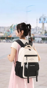 Détail d'un sac à dos imperméable beige et noir avec pendentif étoile et slogan