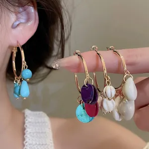 Ethnic style gold hoop earrings set with colorful stone teardrop tassels on model
