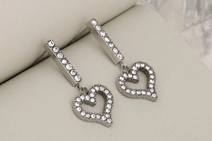 Macro close-up of silver heart drop earrings with full crystal rhinestone pavé detailing