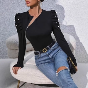 Detail of elegant black top featuring asymmetric zipper and pearl-beaded puff sleeves