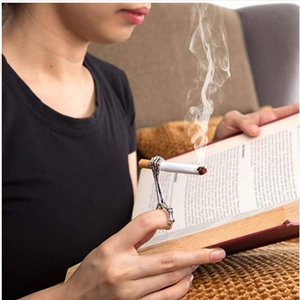 Macro view of skeleton hand cigarette holder ring used while reading a book