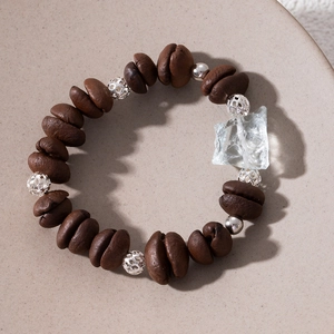 Close-up of creative coffee bean beads and irregular crystal stone on a silver bracelet
