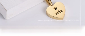 Macro view of a gold-plated heart pendant with crown detail and mae engraving