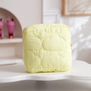 Detail of light yellow quilted makeup bag with cloud patterns and a metal zipper