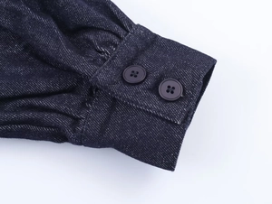 Detailed close-up of the double-buttoned cuffs on a deep blue denim shirt for women