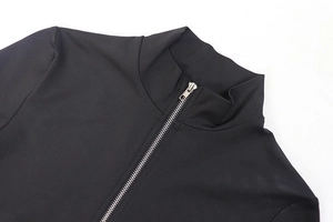 Close-up of black high-neck jumpsuit featuring a silver metal zipper and ribbed texture