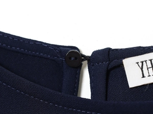 Gros plan de la robe courte bleu marine montrant la texture tissée et le bouton au dos