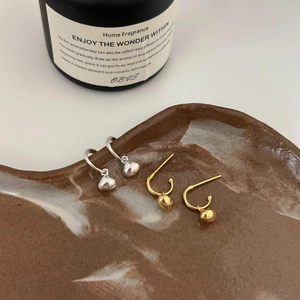 Detailed view of silver and gold teardrop hoop earrings on a ceramic tray