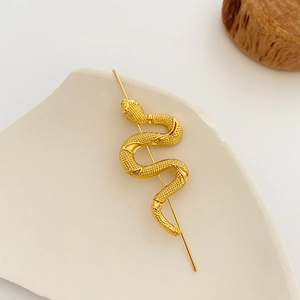Minimalist gold snake-shaped hair pin with realistic scale texture on stone base