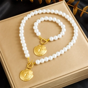 Close-up of pearl necklace and bracelet set with scallop charms on a gold jewelry box