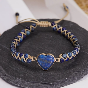 Detail of woven bracelet featuring heart-shaped blue stone and gold trim on black stone