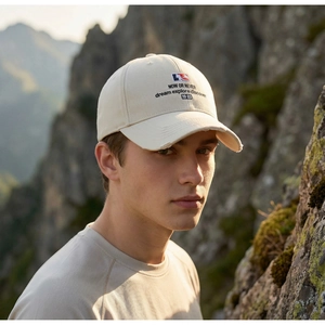 Detail of beige cotton baseball cap featuring embroidered text and distressed brim edges