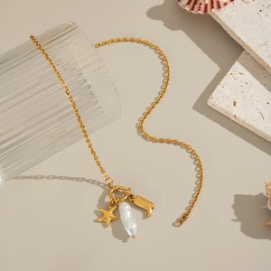 Detail of beach style gold necklace with starfish, baroque pearl and moon pendants