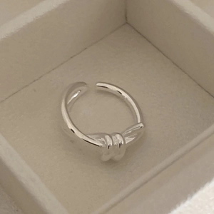 Close-up of a minimalist silver knot ring with a three-loop adjustable open band design