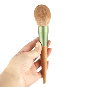 Large fluffy powder brush with natural wood handle and matte green metal ferrule