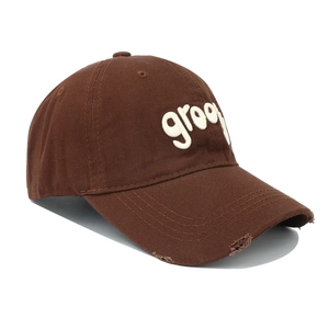 Detailed side view of distressed dark brown baseball cap with white groovy embroidery