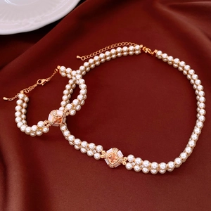 Close-up of double-layer pearl jewelry set with golden gemstone buckle on red silk background