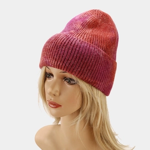 Close-up of tie-dye knit beanie showing pink to orange gradient texture and soft yarn fabric