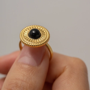 Dettaglio anello regolabile in oro con motivo a raggiera e onice nero centrale