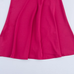 Dettaglio dell'orlo del vestito in raso magenta con trama setosa e drappeggio naturale