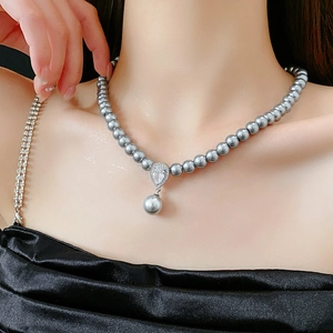 Detail view of a gray pearl necklace featuring a zircon waterdrop pendant on model