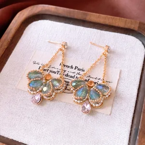 Vintage gold butterfly earrings with green crystals and pearls on linen background