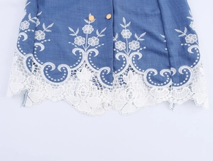Detail von blauem Blazer-Kleid Saum mit weißer Spitze, Blumenstickerei und Goldknöpfen