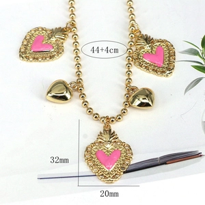 Golden bead chain necklace with pink enamel heart pendant and lace design charms