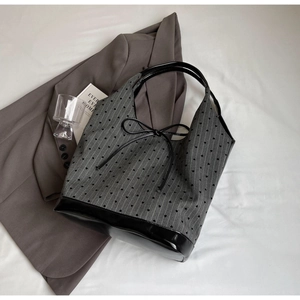 Close-up of gray striped tote bag with black heart patterns and shiny faux leather base