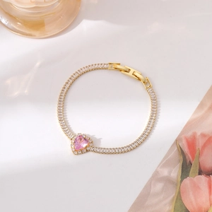 Detail of gold bracelet with sparkling pink heart gemstone and pavé cubic zirconia