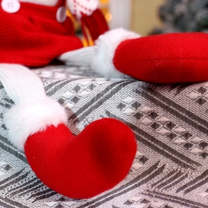 Détail des chaussures en feutre rouge et jambes tricotées d'une poupée de Noël