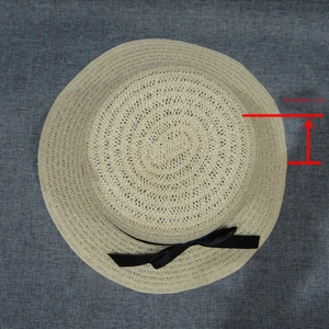 Detail view of wide brim straw hat showing 17cm height and black ribbon bow decoration