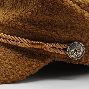 Detail of brown faux shearling navy cap with gold braided rope and embossed metal button