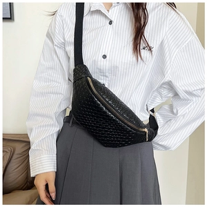 Détail de la texture tressée noire du sac de poitrine avec fermeture éclair dorée