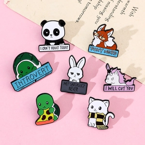 Macro shot of cartoon animal enamel pins including panda and fox on pink background