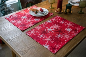 Close-up of red Christmas placemats with snowflake patterns on a rustic wooden table