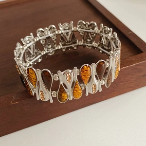Detail view of vintage amber teardrop stretch bracelet with crystals on wooden background