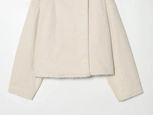 Detailed macro view of cream plush faux fur jacket texture and matching round button
