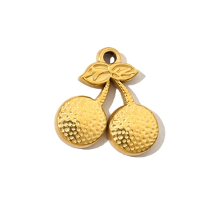 Macro shot of golden cherry pendant with textured hammered finish on a white background
