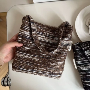 Detail of striped knit tote bag showing thick texture and white simple wish label