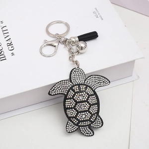 Detail of turtle keychain featuring black tassels and shimmering crystal rhinestones