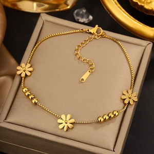 Detail of gold box chain bracelet with daisy charms and polished round beads