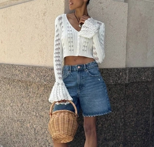 Detail of white hollow-out crochet knit cardigan with stylish flared long sleeves