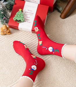 Close-up of festive red Christmas socks with cartoon Santa patterns and white faux fur trim