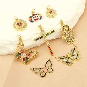 Collection of gold-plated 18K pendants including butterflies, cross, and Hamsa hand motifs